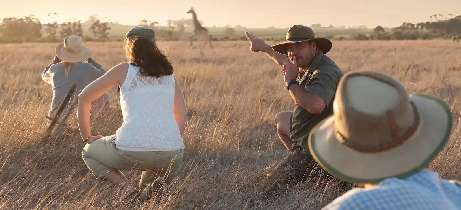 Tour guide showing a giraffe to a group on safari